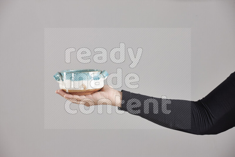 A woman in black abaya holding different pottery essentials in different positions