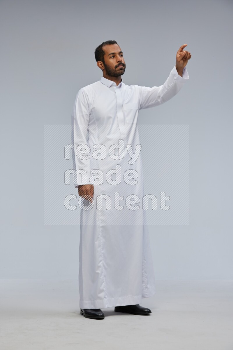 Saudi man Wearing Thob standing interacting with the camera on Gray background