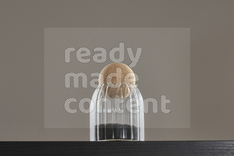 Black seeds in a glass jar on black background