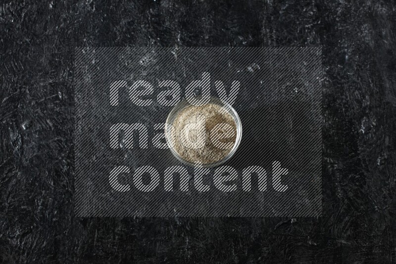 وعاء زجاجي ممتلئ ببودرة الهيل علي خلفية سوداء