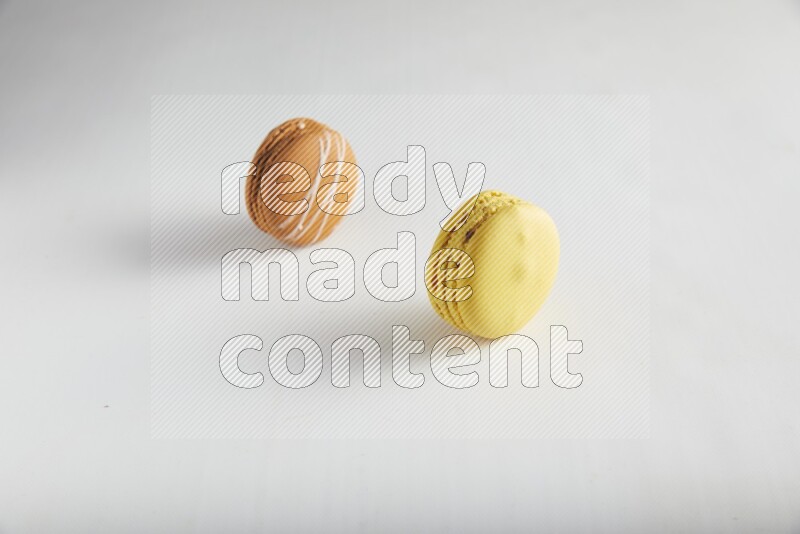 45º Shot of of two assorted Brown Irish Cream, and Yellow Lemon macarons on white background