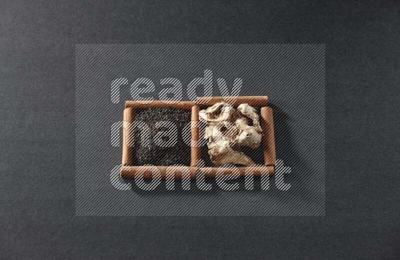 2 squares of cinnamon sticks full of dried ginger and black tea on black flooring