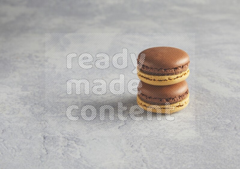45º Shot of two Yellow and Brown Chai Latte macarons r on white  marble background