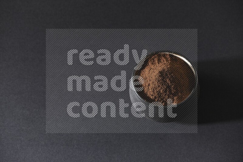 وعاء فخاري أسود ممتلئ ببودرة القرنفل علي خلفية سوداء