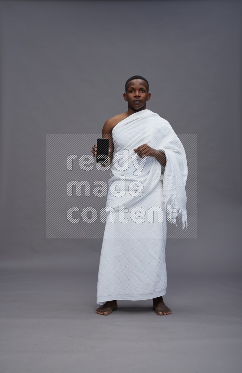 A man wearing Ehram Standing showing phone to camera on gray background