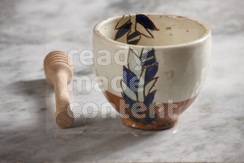Decorative pottery bowl with wooden honey dipper on the side on grey marble background