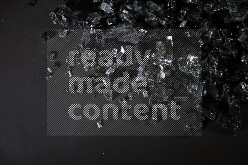 Transparent black fragments of glass scattered on a black background