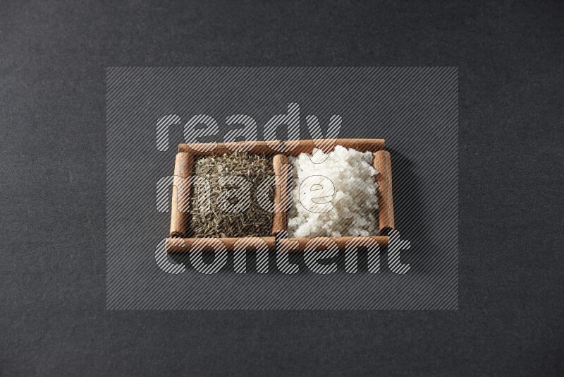 2 squares of cinnamon sticks full of white salt and cumin on black flooring
