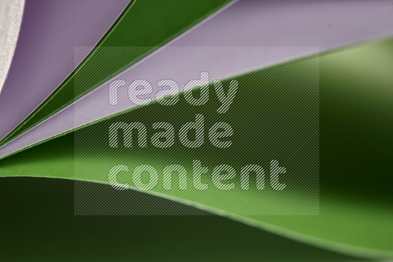 An abstract art showing purple and green paper sheets arranged in an overlapping curves