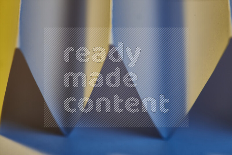 A close-up abstract image showing sharp geometric paper folds in blue gradients and warm tones