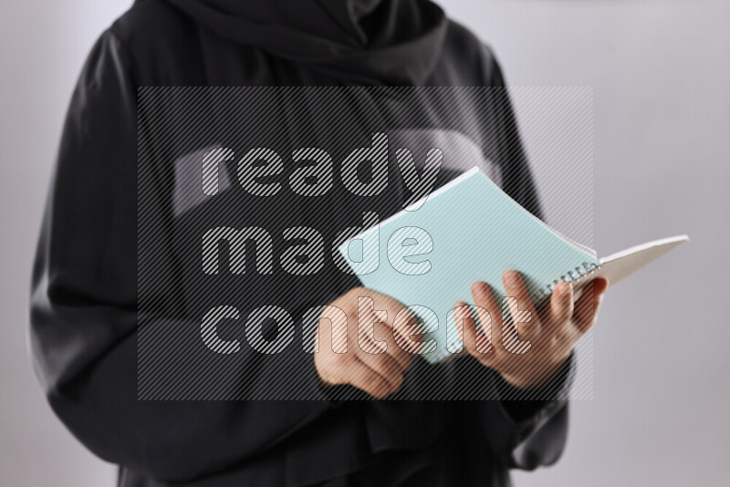A woman in abaya holding books and a board in different positions (back to school)