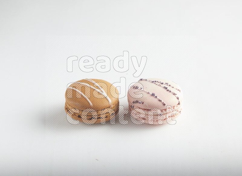 45º Shot of of two assorted Brown Irish Cream, and pink orange blossom macarons on white background
