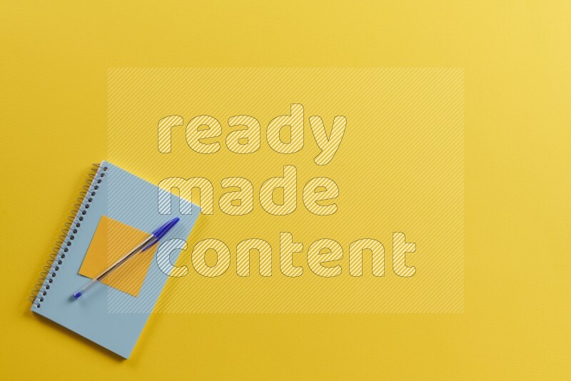 A blue notebook with different school supplies on yellow background