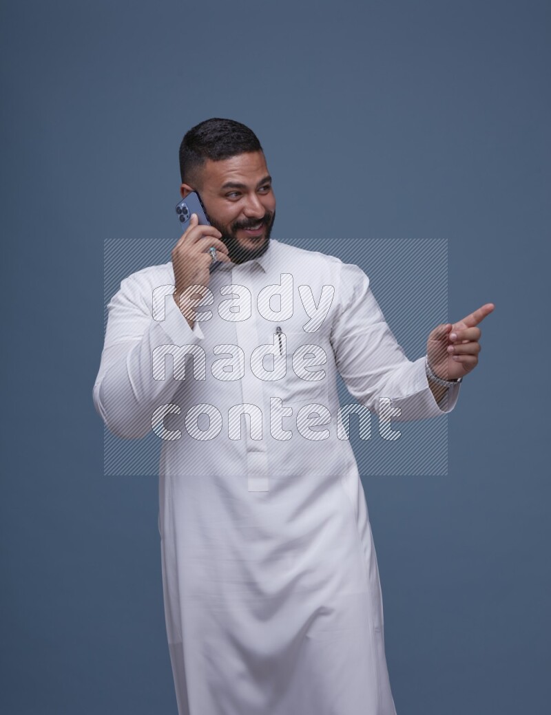 A Saudi man calling on blue background wearing Saudi Thob