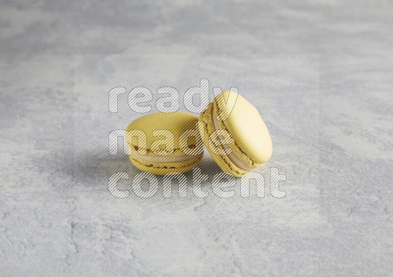 45º Shot of two Yellow Lime macarons  on white  marble background