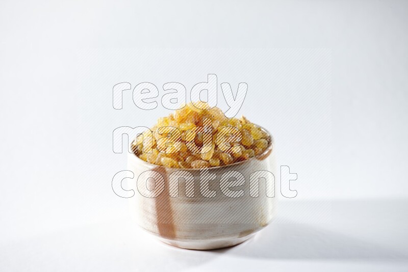 A beige ceramic bowl full of raisins on a white background in different angles