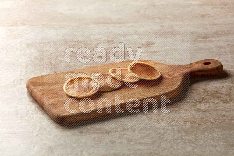 Four stacked plain mini pancakes on a wooden board on beige background