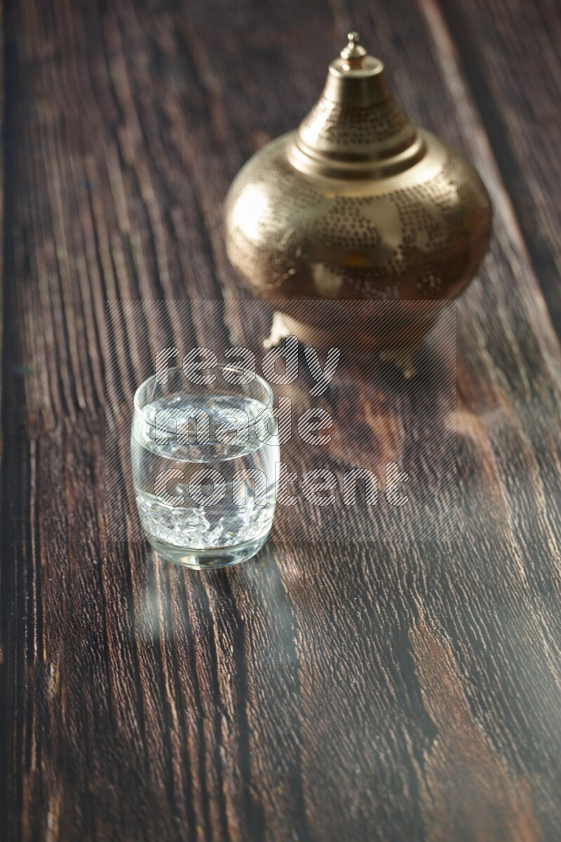 A golden lantern with different drinks, dates, nuts, prayer beads and quran on brown wooden background