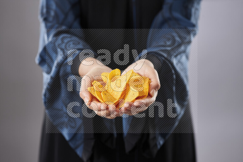 Woman in abaya holding different kinds of snacks in different positions
