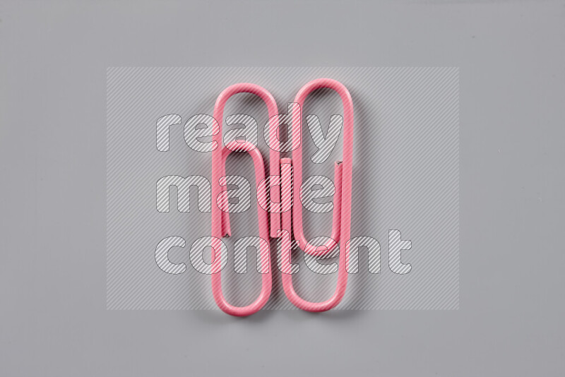 Pink paper clips isolated on a grey background