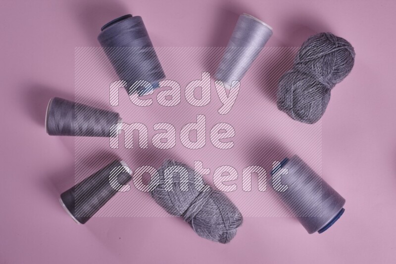 A grey collection of sewing and tailoring tools arranged on a pink background