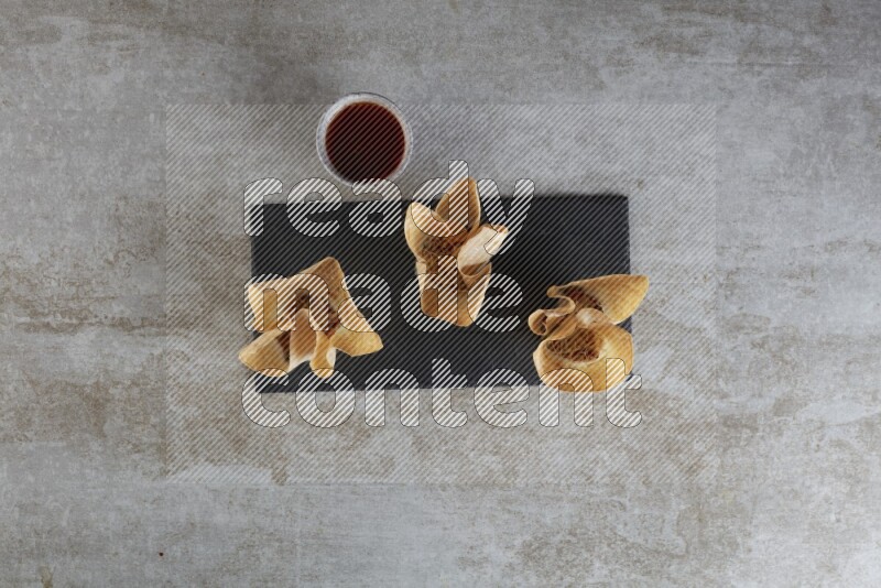 wonton cups with soy sauce ramkin on rectangle slate on grey textured counter top