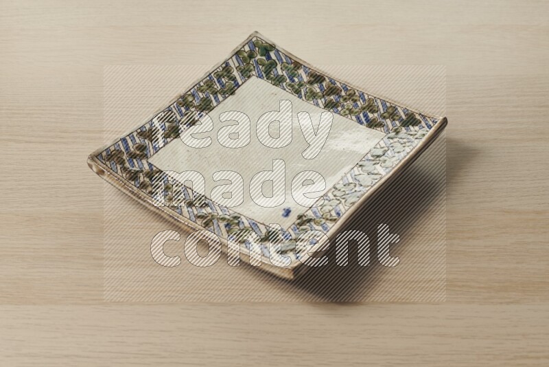 A decorative pottery plate on light wooden background