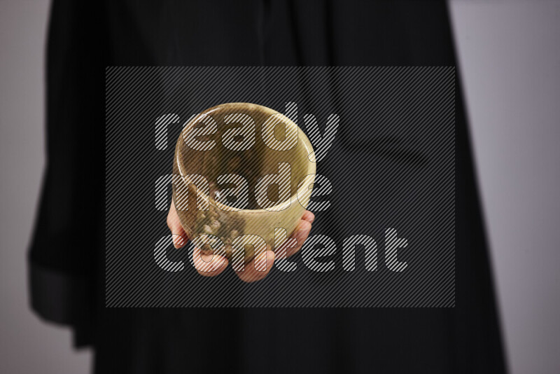 A woman in black abaya holding different pottery essentials in different positions