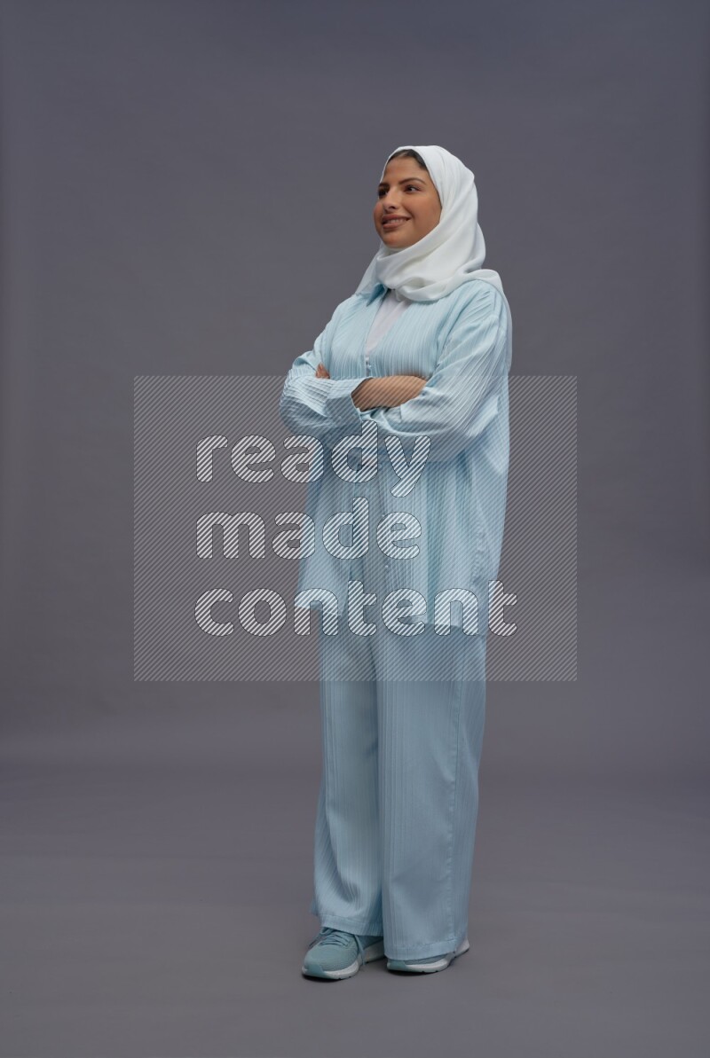 Saudi woman wearing hijab clothes standing with crossed arms on gray background