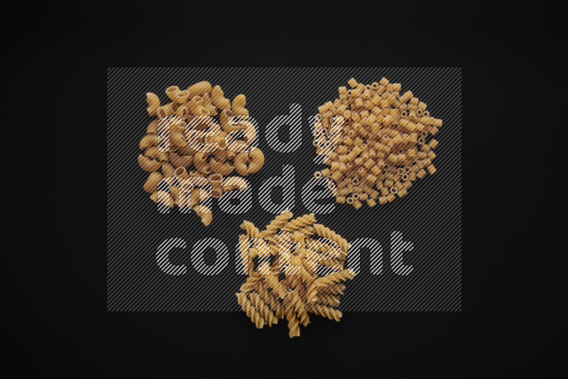 Different pasta types in bunches on black background