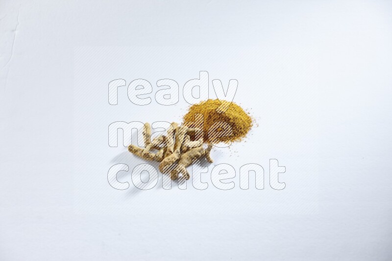 Turmeric powder and dried turmeric whole fingers on white flooring
