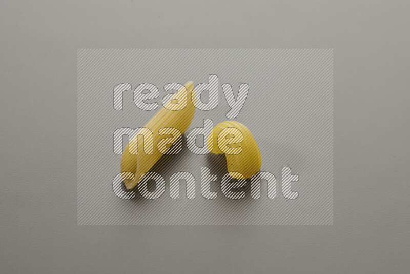 Penne pasta with other types of pasta on grey background