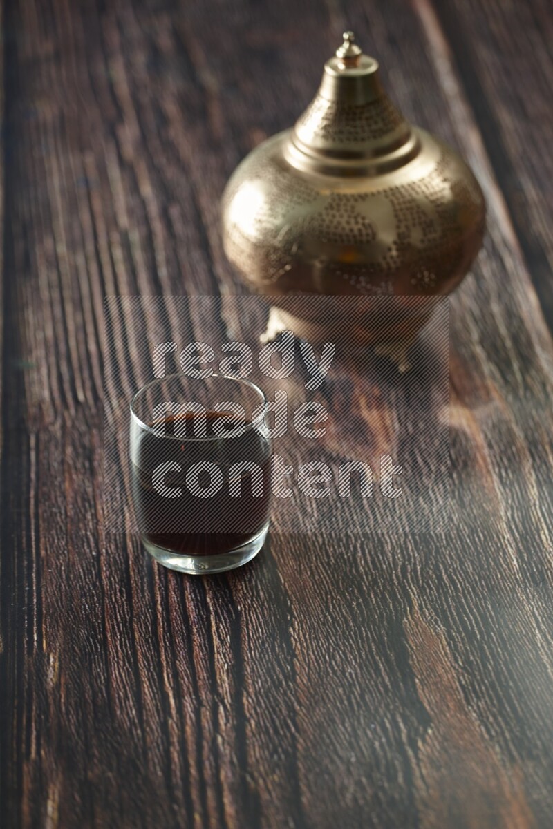 A golden lantern with different drinks, dates, nuts, prayer beads and quran on brown wooden background