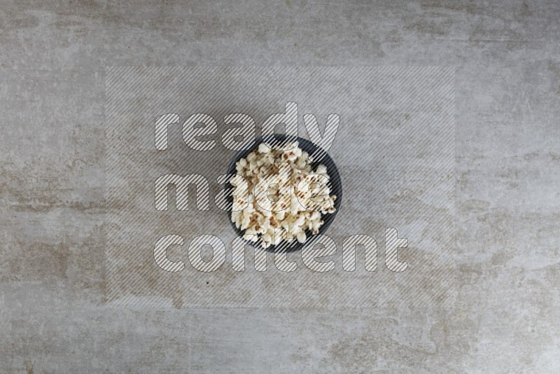 popcorn in black bowl on a grey textured countertop