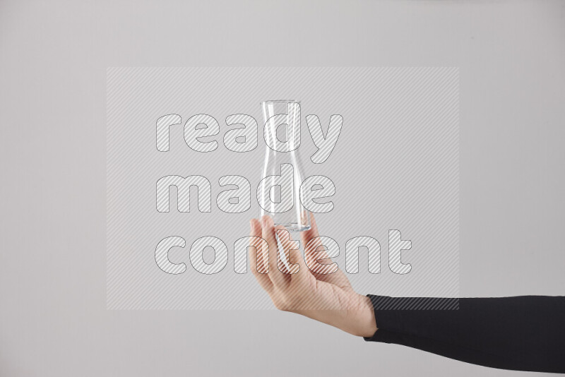 A woman in black abaya holding different glassware in different positions