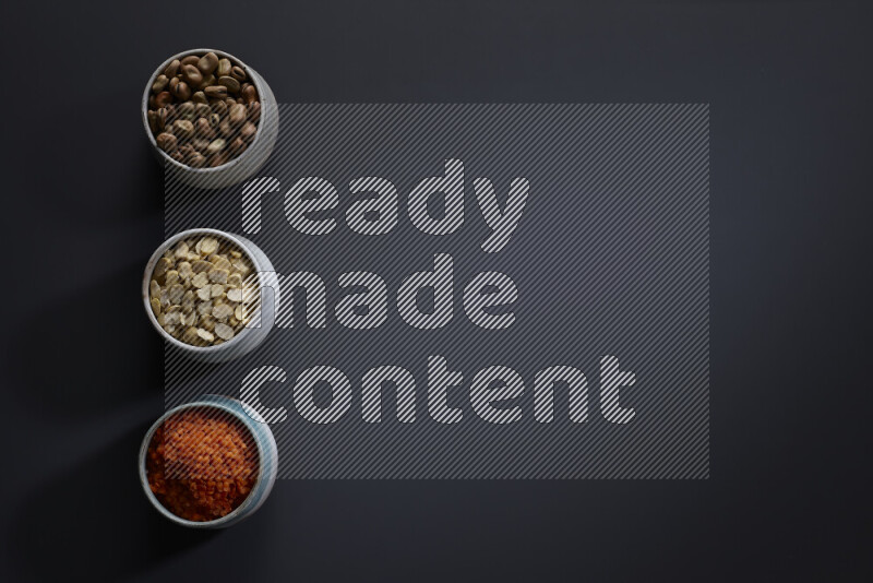 Legumes in pottery bowls on grey background
