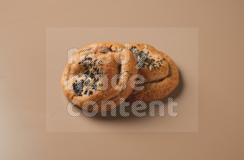 Two chocolate chip cookies on a brown background