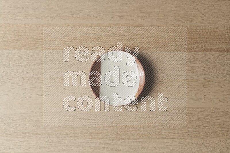 A multicolored pottery plate on light wooden background