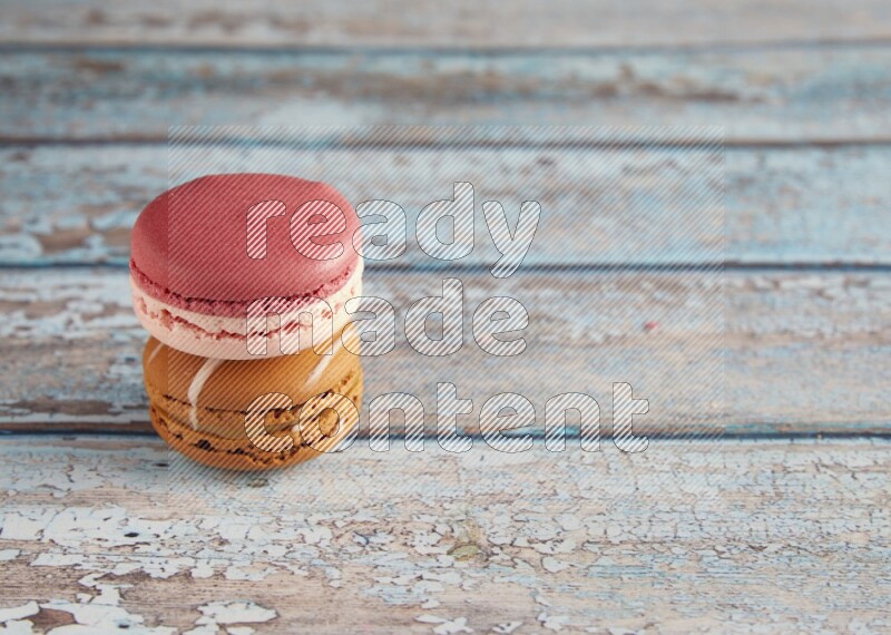 45º Shot of of two assorted Brown Irish Cream, and Pink Litchi Raspberry macarons on light blue background