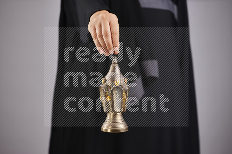 A woman in black abaya holding different ramadan lanterns in different positions