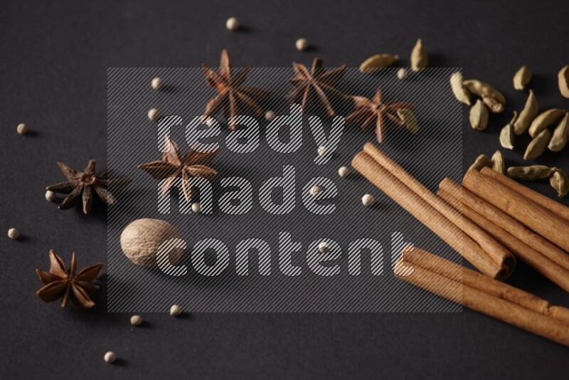 Cinnamon sticks, cardamom, star anise, nutmeg and white peppers on a black background
