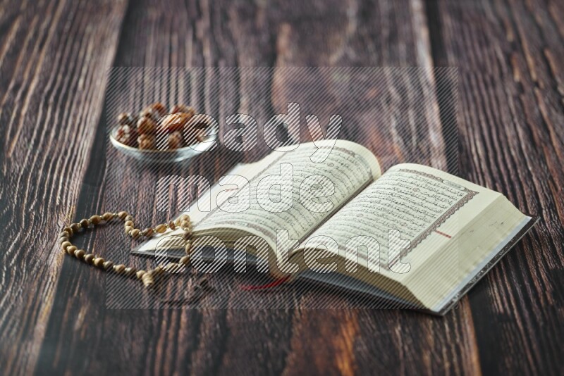 Quran with dates, prayer beads and different drinks all placed on wooden background