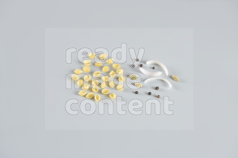 Raw pasta with different ingredients such as cherry tomatoes, garlic, onions, red chilis, black pepper, white pepper, bay laurel leaves, rosemary, cardamom and mushrooms on light blue background