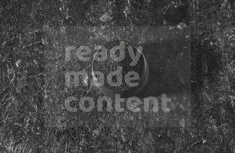 وعاء فخاري أسود ممتلئ ببذور حبة البركة علي خلفية سوداء