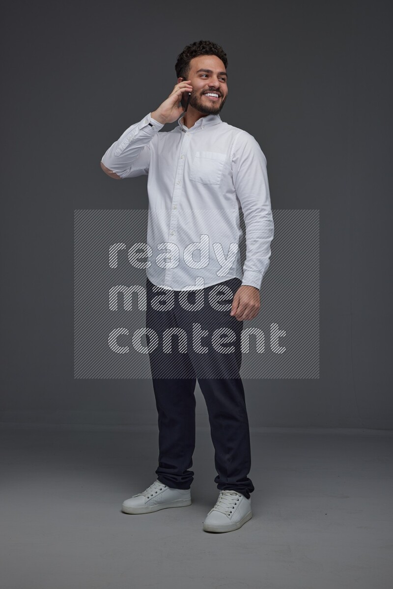 A man wearing smart casual talking in the phone eye level on a gray background