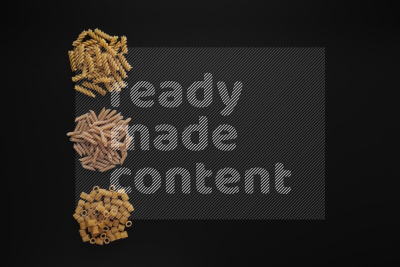 Different pasta types in 3 bunches on black background