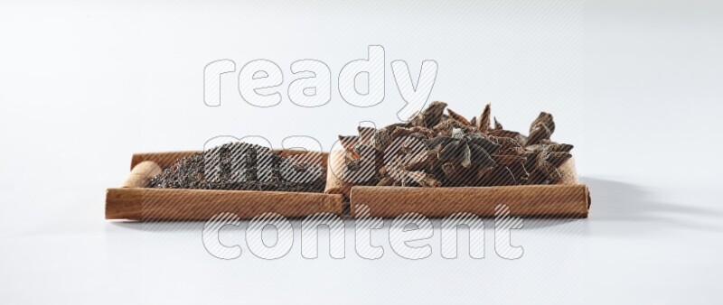 2 squares of cinnamon sticks full of black tea and star anise on white flooring