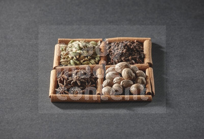 4 squares of cinnamon sticks full of cardamom, star anise, nutmegs and cloves on black flooring