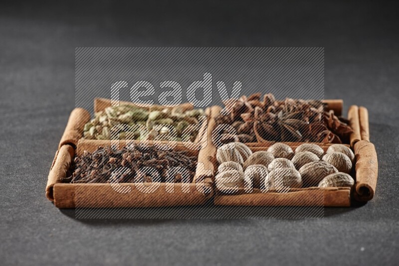 4 squares of cinnamon sticks full of cardamom, star anise, nutmegs and cloves on black flooring