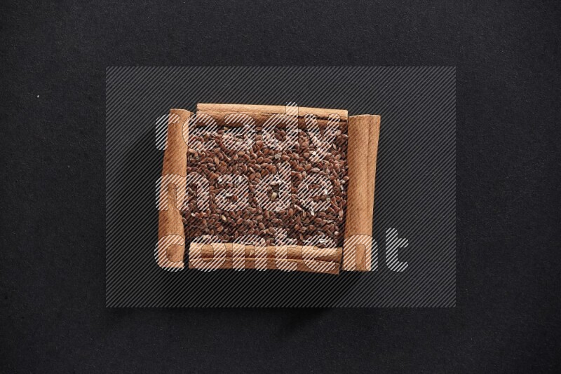 A single square of cinnamon sticks full of flaxseeds on black flooring